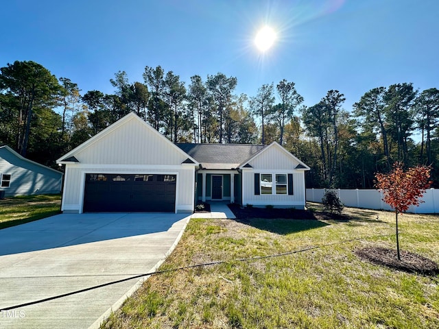 view of front facade featuring a front yard, fence, driveway, a garage, and board and batten siding