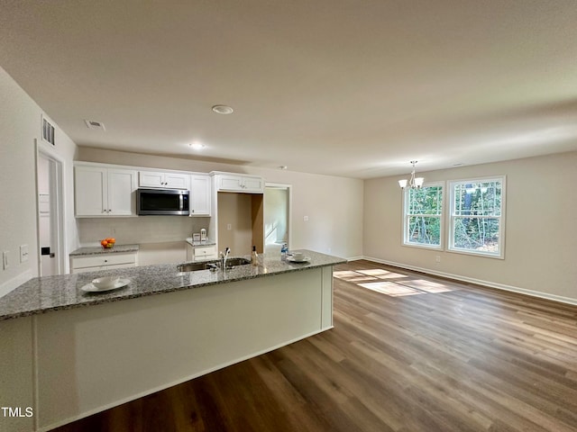 kitchen with pendant lighting, sink, hardwood / wood-style flooring, white cabinetry, and dark stone counters