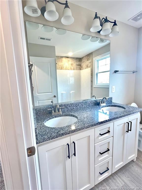 bathroom featuring hardwood / wood-style floors, toilet, vanity, and walk in shower