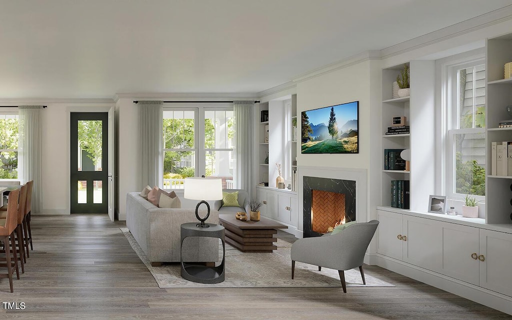 living area featuring built in features, light wood finished floors, ornamental molding, and a fireplace