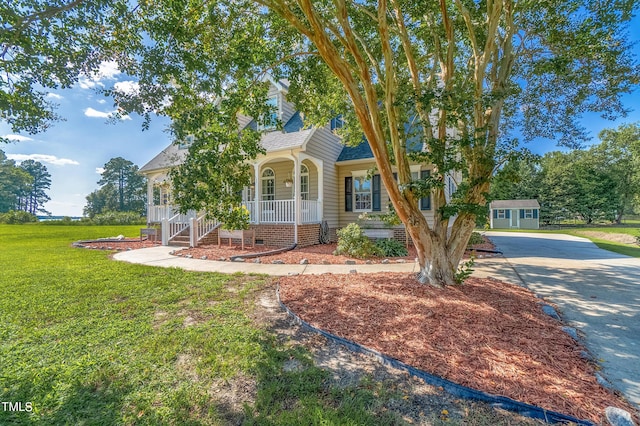 view of front of property with an outbuilding, a porch, a shingled roof, crawl space, and a front lawn