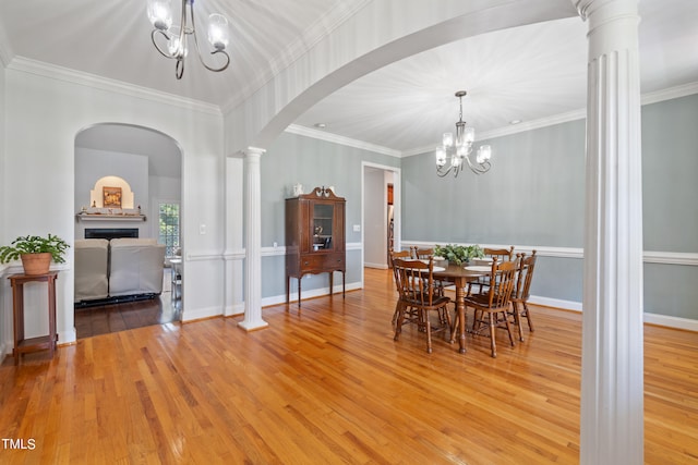 dining space featuring arched walkways, wood-type flooring, and a notable chandelier