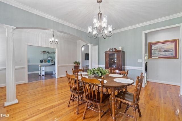 dining room with arched walkways, a notable chandelier, light wood-type flooring, ornate columns, and crown molding