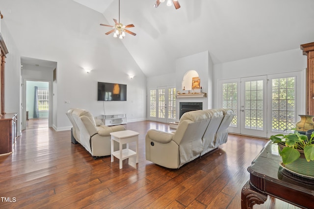 living room with ceiling fan, high vaulted ceiling, dark wood-style flooring, a fireplace, and baseboards