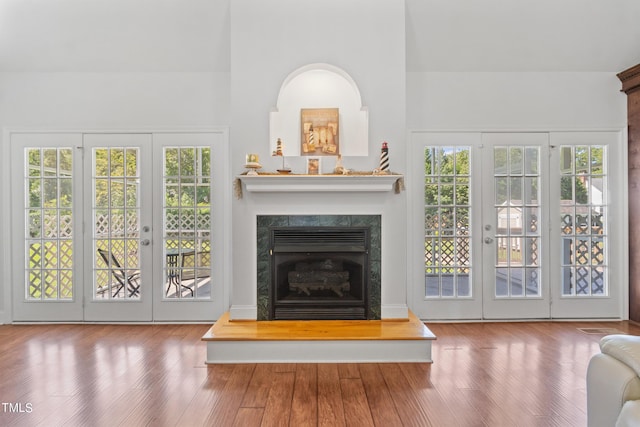 unfurnished living room with french doors, a fireplace, and wood finished floors