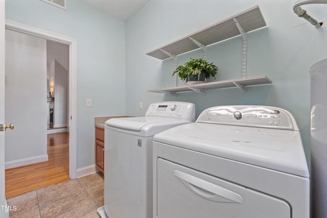 laundry room featuring cabinet space, baseboards, washer and dryer, and light tile patterned flooring