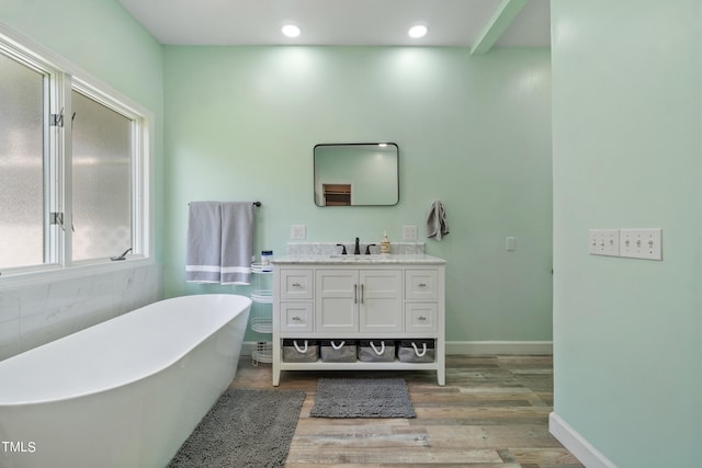 bathroom featuring a freestanding bath, wood finished floors, vanity, and recessed lighting