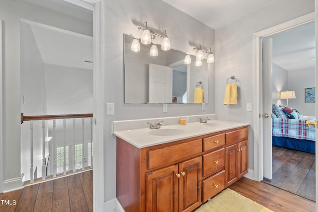 ensuite bathroom with connected bathroom, double vanity, a sink, and wood finished floors