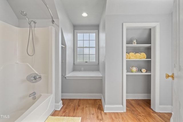 full bathroom featuring built in shelves, washtub / shower combination, baseboards, and wood finished floors