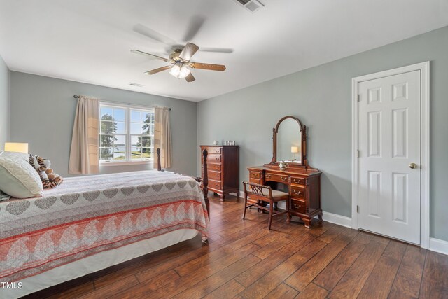 bedroom with dark wood-style floors, visible vents, ceiling fan, and baseboards