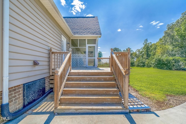 doorway to property with a deck, roof with shingles, and a lawn