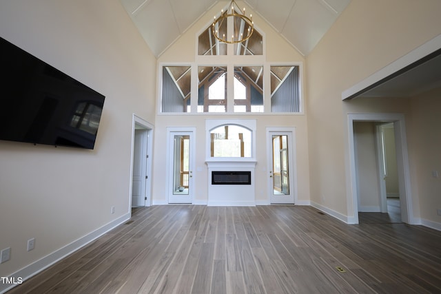 entrance foyer with high vaulted ceiling, hardwood / wood-style floors, and a chandelier