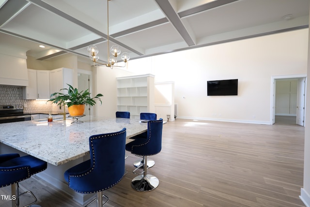 kitchen featuring a breakfast bar area, decorative backsplash, light wood-type flooring, and white cabinetry