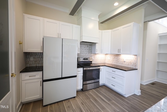 kitchen with tasteful backsplash, wood-type flooring, white cabinets, white fridge, and stainless steel range with electric stovetop