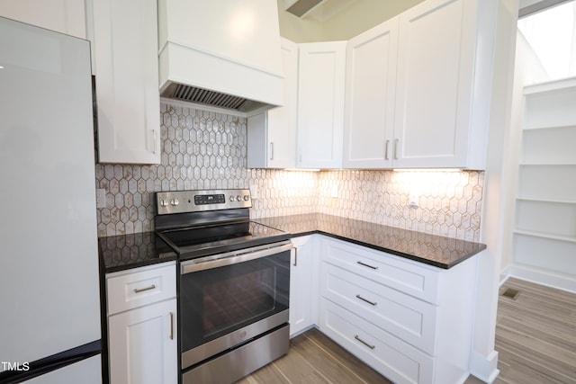 kitchen featuring premium range hood, tasteful backsplash, electric stove, white cabinets, and white fridge