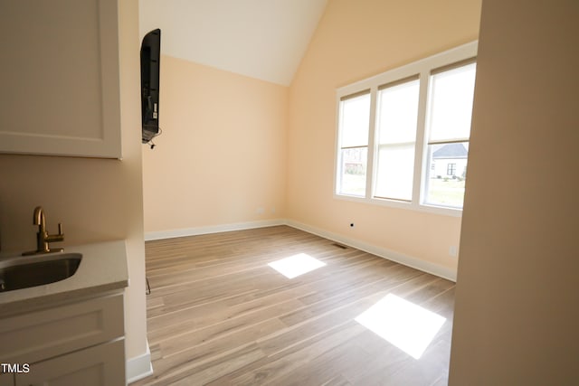 interior space featuring sink, vaulted ceiling, and light wood-type flooring