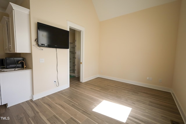 unfurnished living room with sink, high vaulted ceiling, and light hardwood / wood-style flooring