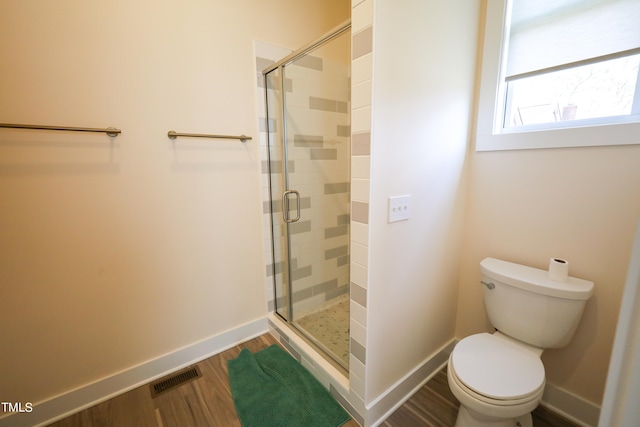 bathroom with a shower with shower door, toilet, and wood-type flooring