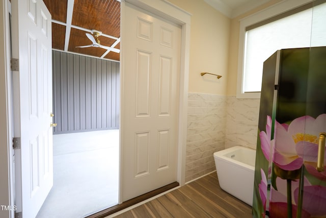 bathroom featuring tile walls, a bath, and hardwood / wood-style flooring