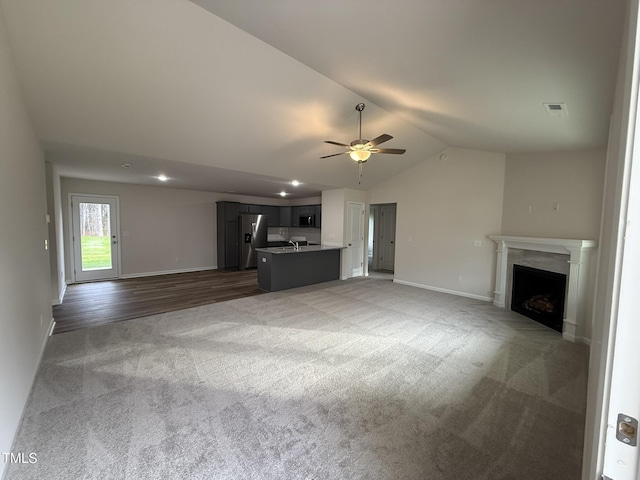 unfurnished living room with dark carpet, ceiling fan, and lofted ceiling