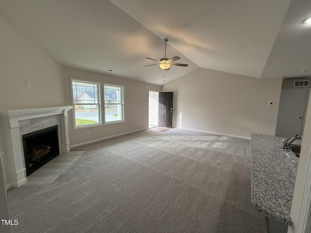 unfurnished living room featuring light carpet, ceiling fan, sink, a tile fireplace, and lofted ceiling