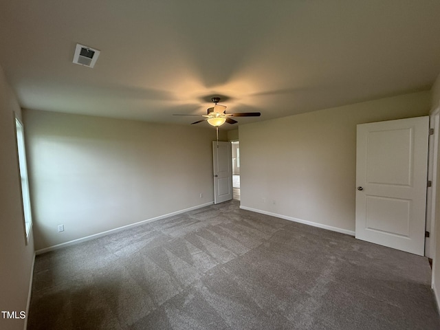 spare room featuring ceiling fan and dark carpet