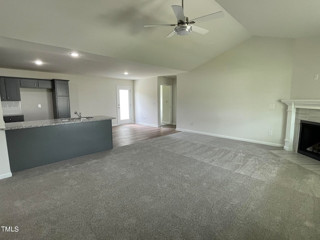 unfurnished living room with carpet, ceiling fan, vaulted ceiling, and sink