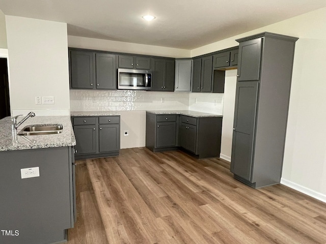 kitchen with light stone countertops, gray cabinetry, dark hardwood / wood-style floors, and sink