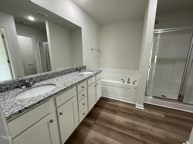 bathroom featuring wood-type flooring, vanity, and plus walk in shower