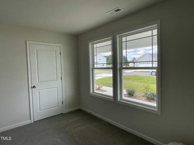 spare room with dark carpet and a healthy amount of sunlight