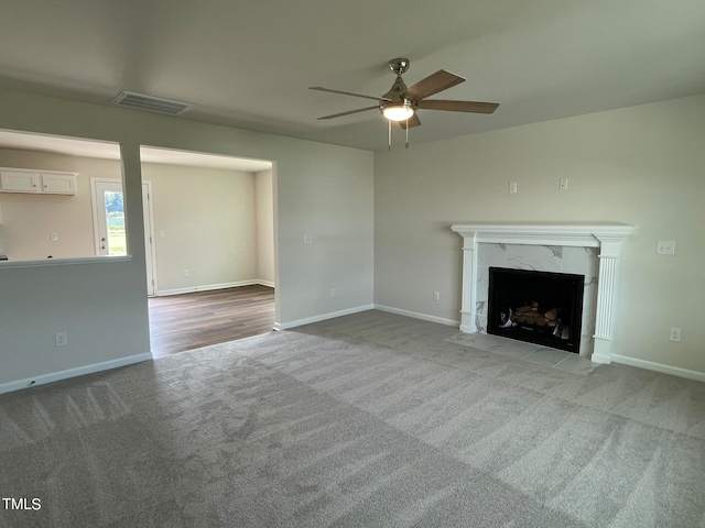 unfurnished living room featuring ceiling fan, a fireplace, and light carpet