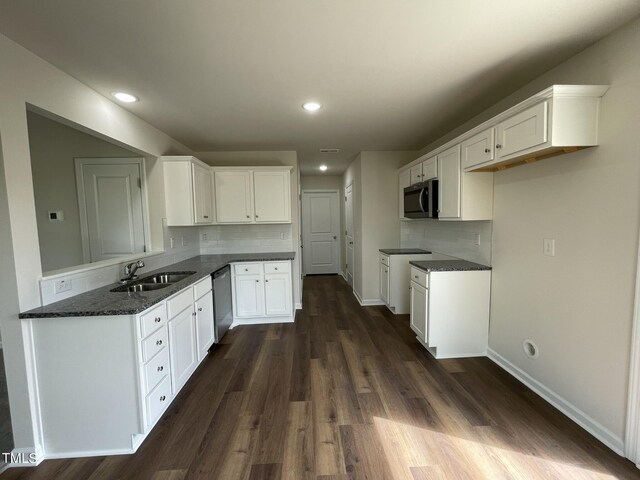 kitchen featuring dark hardwood / wood-style floors, appliances with stainless steel finishes, tasteful backsplash, sink, and white cabinetry