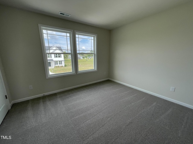 spare room with dark carpet, baseboards, and visible vents