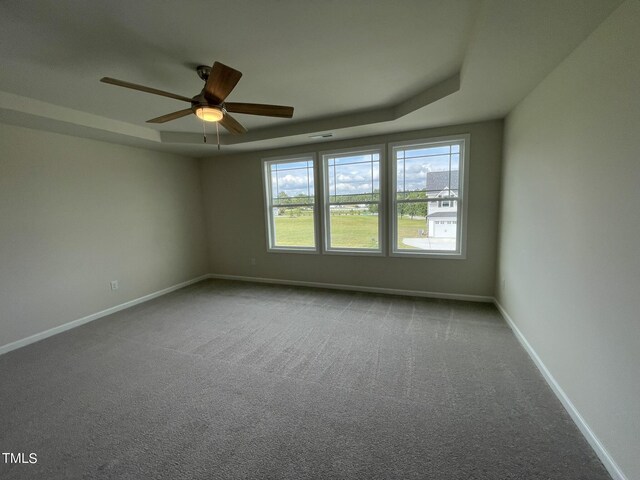 carpeted spare room featuring a raised ceiling and ceiling fan