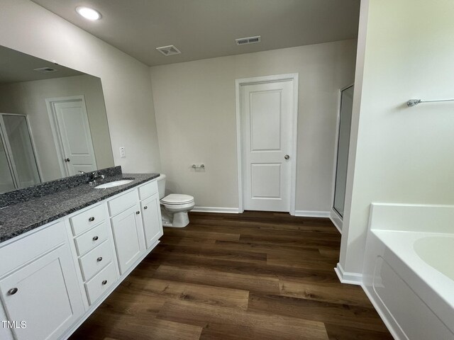 full bathroom with hardwood / wood-style floors, separate shower and tub, toilet, and vanity