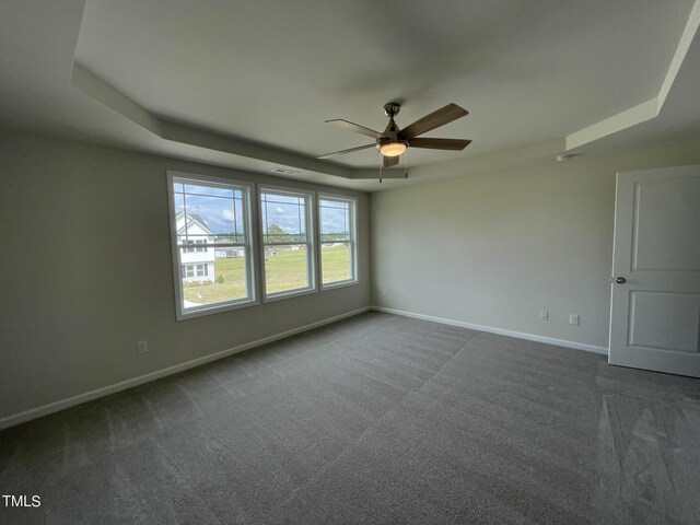 carpeted empty room featuring a tray ceiling and ceiling fan