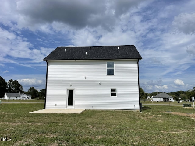 back of property featuring roof with shingles, a yard, and a patio