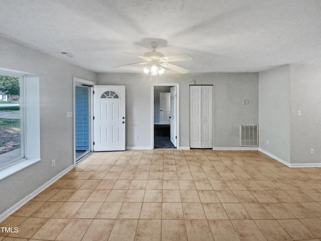 empty room with a ceiling fan, visible vents, a textured ceiling, and baseboards