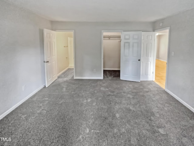 unfurnished bedroom with dark colored carpet and baseboards