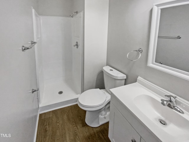 bathroom featuring toilet, wood finished floors, vanity, and a shower stall