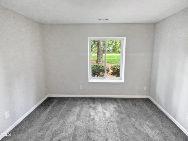 spare room featuring baseboards, visible vents, and dark carpet