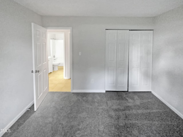 unfurnished bedroom with a closet, dark carpet, and baseboards