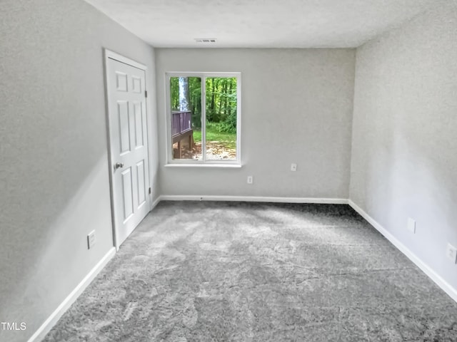 carpeted spare room with visible vents and baseboards