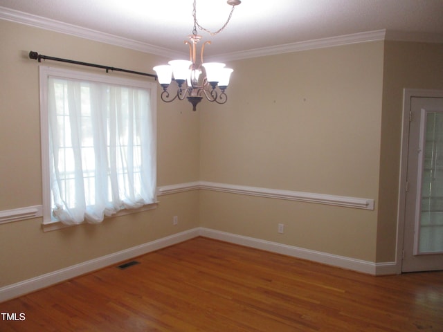 unfurnished room featuring hardwood / wood-style floors, ornamental molding, and a chandelier