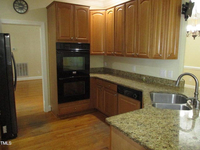 kitchen featuring sink, black appliances, light stone counters, and hardwood / wood-style flooring