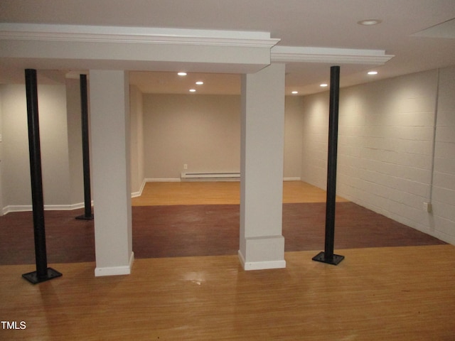 basement featuring light wood-type flooring and a baseboard heating unit