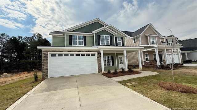 view of front of home with a garage, concrete driveway, stone siding, covered porch, and a front lawn