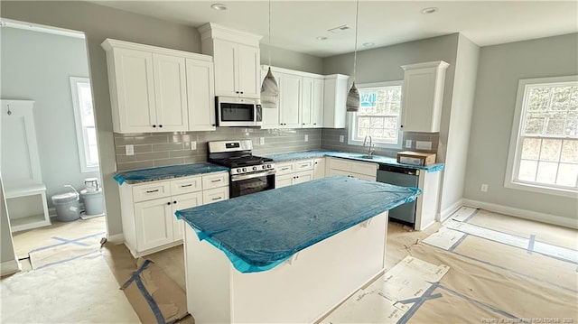 kitchen with stainless steel appliances, tasteful backsplash, white cabinetry, and a center island