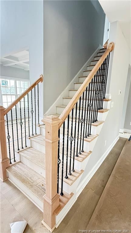 stairs with coffered ceiling, wood finished floors, beam ceiling, and baseboards