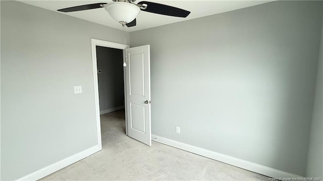 empty room with a ceiling fan, baseboards, and concrete flooring